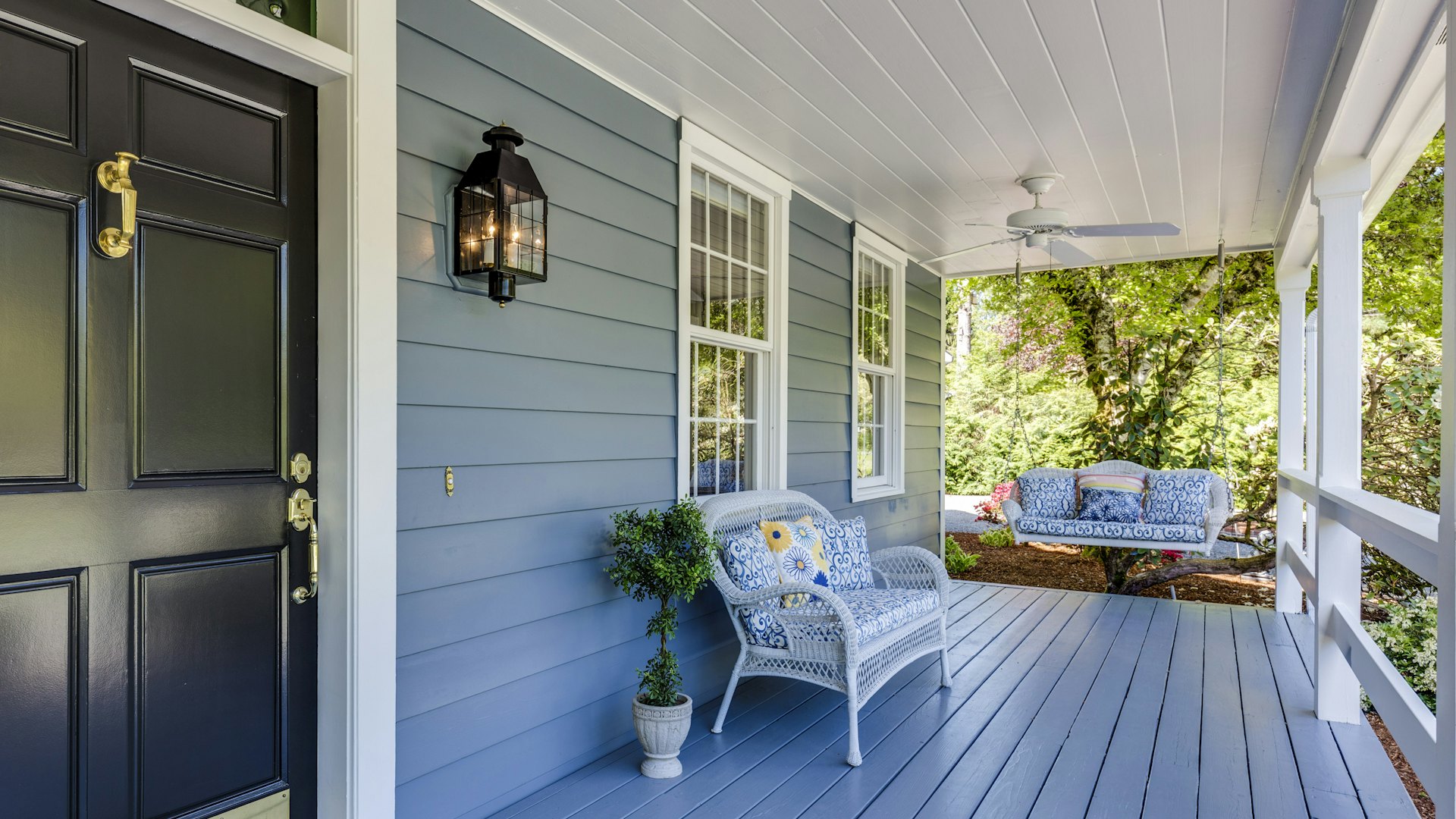 A black front door and windows on a blue clapboard porch