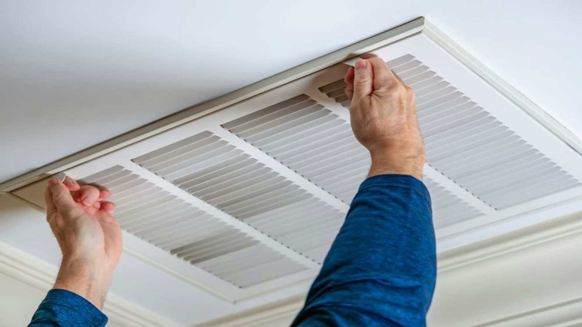 Hands replacing a ceiling air filter