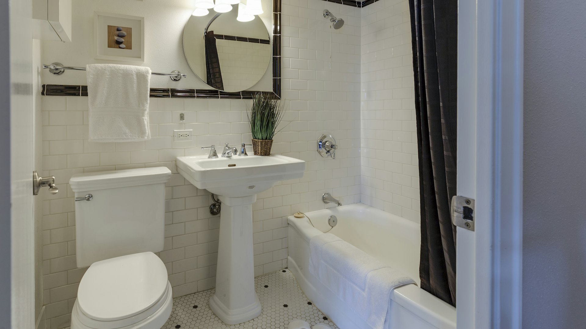 A tiled bathroom with tub and pedestal sink