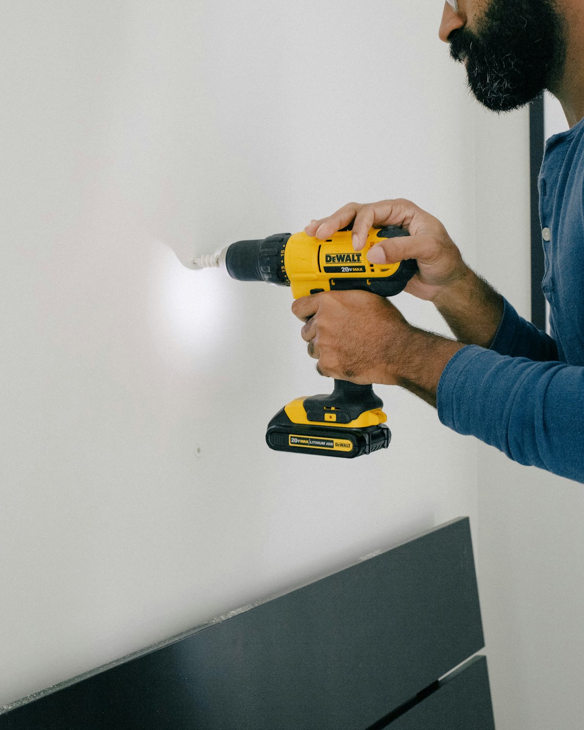 A tradesman drilling a clean pilot hole in a white wall.