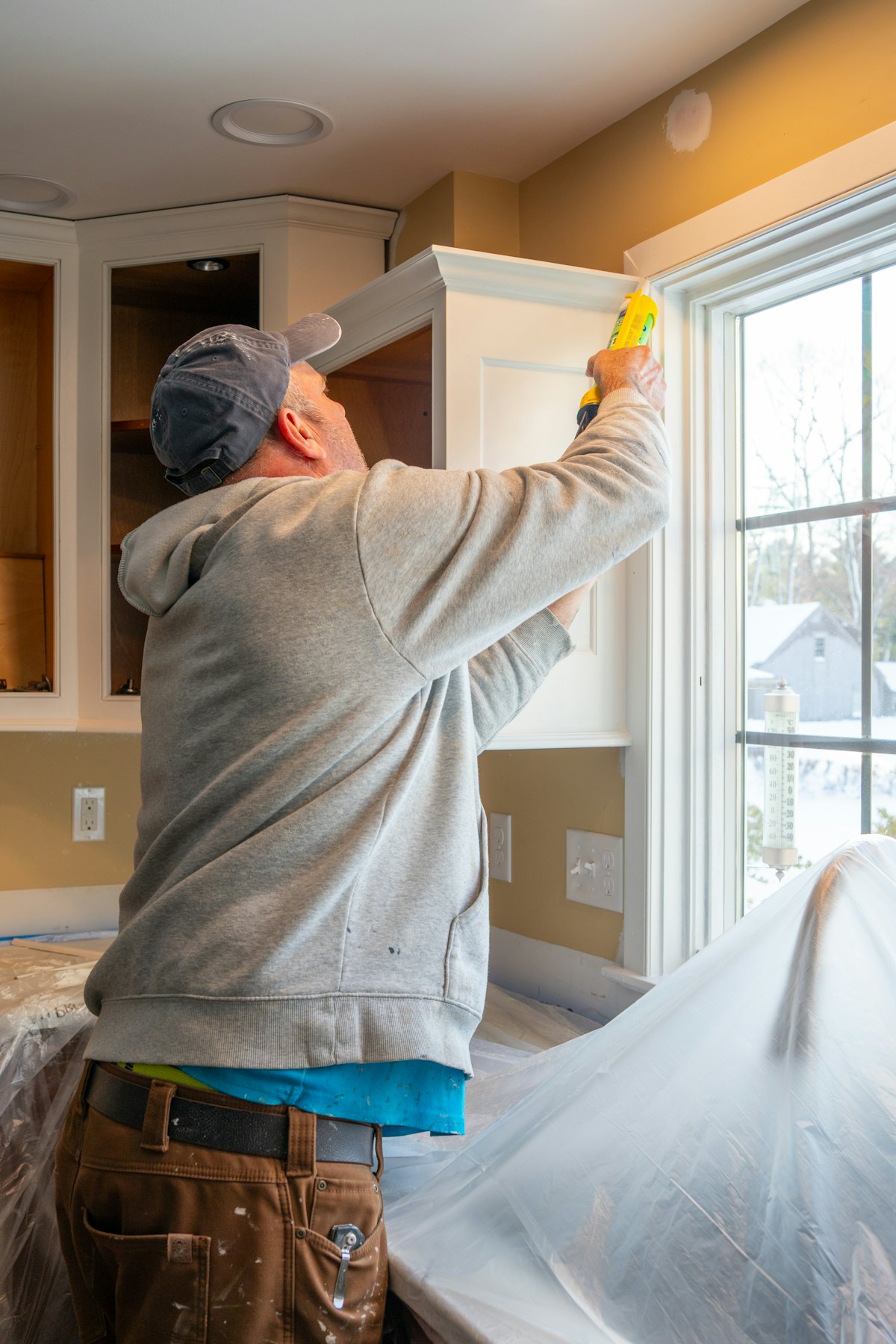 A tradesman caulking a window frame inside a home